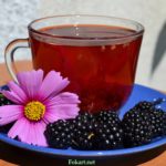 Чашка чая с добавлением свежих плодов ежевики и цветок космеи