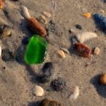 Морские камешки на мокром песке после отхода волны