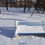 Заснеженная скамейка и сугробы в парке после сильного снегопада
